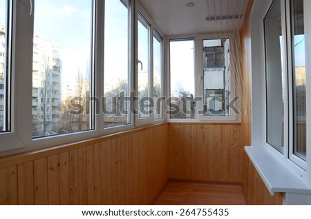 Balcony with the windowed parapet after reconstruction. Interior of a balcony made with tinted pine paneling