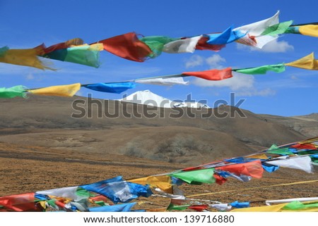 Prayer flags flying over snow mountain on Tibetan Plateau