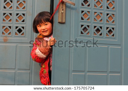 Cute kid hiding behind the door and peeking