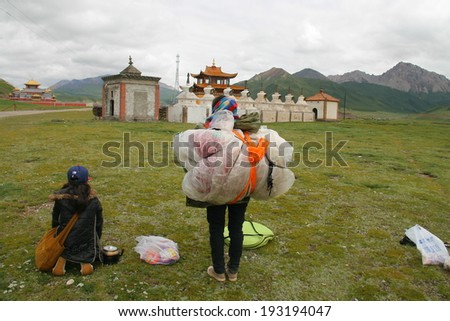 GUOLUO, CHINA - JULY 26: Unidentified mother and daughter kneel down before white stupas in Gerisi temple when circle the holy mountain Anymachen on Tibetan Plateau. July 26, 2013,Guoluo,Qinghai,China