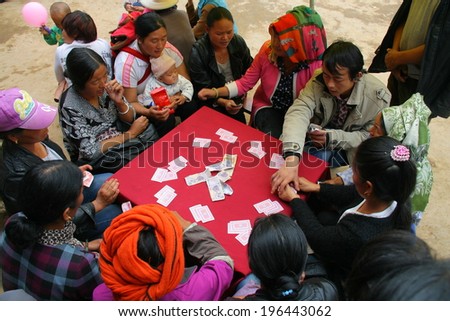 LIJIANG, CHINA - SEPTEMBER 19: Unidentified Mosuo Minority People sit around a table and play gold flower, September 19, 2013, Yongning, Linlang, Lijiang, Yunnan, China