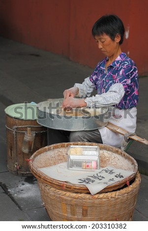 CHENGDU, CHINA - JULY 5: Unidentified woman makes and sells Asparagus Crisp, so called longxusu, a special Chinese dessert, near Wenshu monastery on July 5, 2014, Chengdu, Sichuan, China.