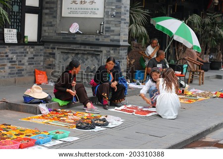 CHENGDU, CHINA - JULY 5: Unidentified minority women sell handcrafts to tourists near Wenshu monastery on July 5, 2014, Chengdu, Sichuan, China.