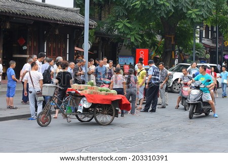 CHENGDU, CHINA - JULY 5: Unidentified crowds watch the argument between a grape seller and buyer, a policeman mediate the dispute, near Wenshu monastery on July 5, 2014,Chengdu, China.