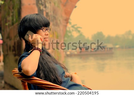 Young lady making a cell phone call when she spends a vacation in an ancient town