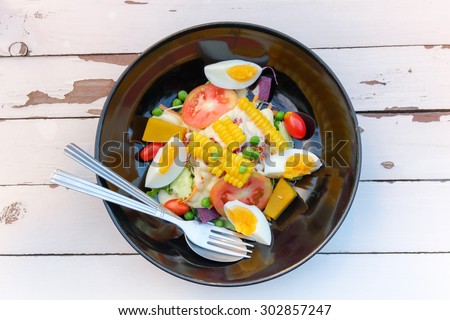 Salad of egg,corn, tomatoes, cucumbers, olives on a plate.Top View.