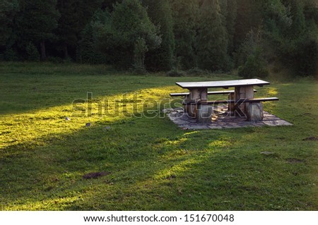 picnic table on countryside with sun beams on grass