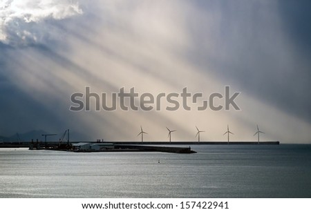 windmill on sea with sun rays