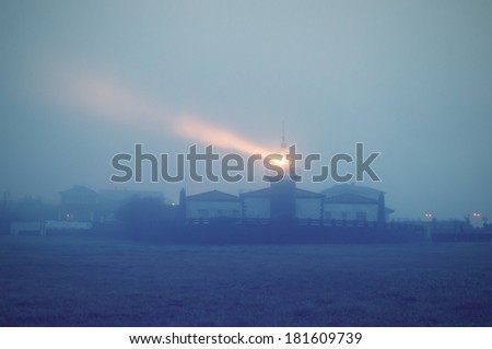 lighthouse at night with fog illuminated with vintage effect