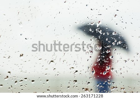 raindrops on window with person with umbrella