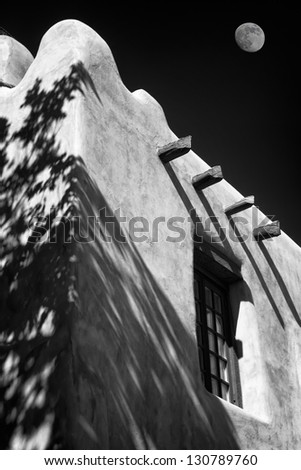 Adobe building in downtown Santa Fe, New Mexico, USA with the moon in the background sky
