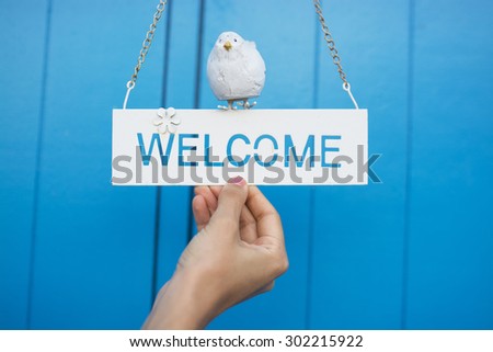 woman holding welcome sign on blue background