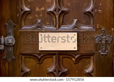 Ancient carved door with empty wooden tablet