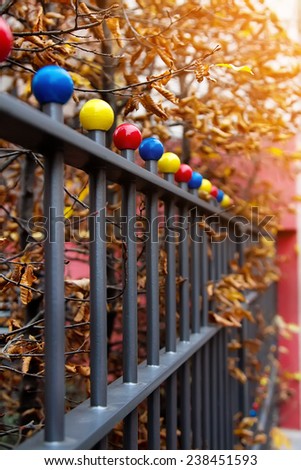 Iron fence with multi colored decorative balls, autumn scene