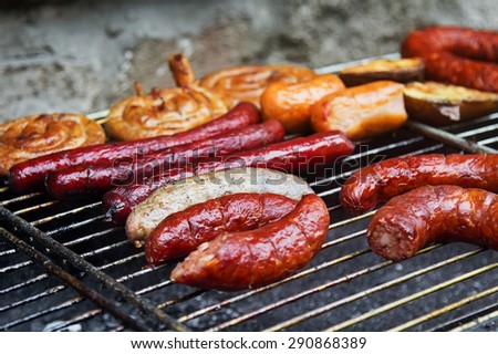 Assortment of grilled sausages and wurst on big grill. Selective focus on the white sausage.
