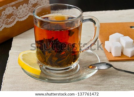 Cup of hot black tea with slice of lemon, sugar and salted biscuits