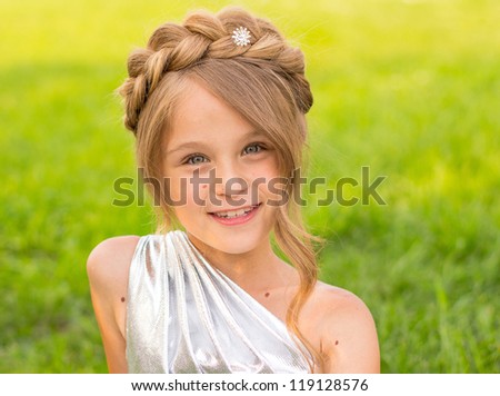 Girl of eight years in a silver dress on a green background