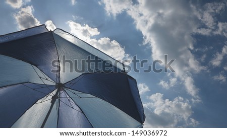 protection from sun under white clouds and a sun umbrella beautiful hot day with blue sky and bright sun