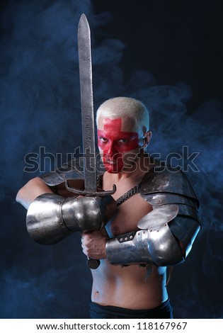 Young knight with iron sword on a black background