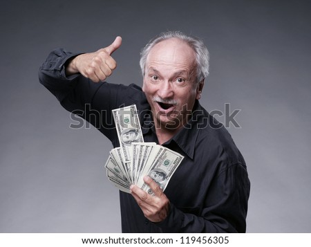 Happy old man with money showing yes sign on a grey background