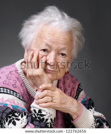 Old sad woman on a gray background