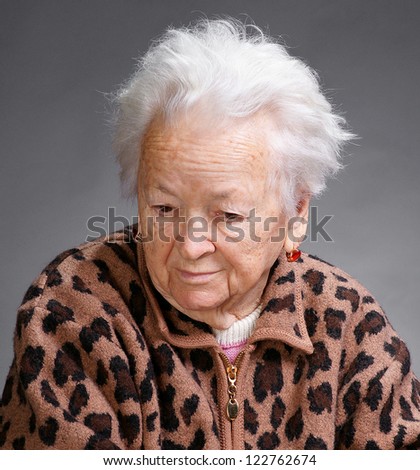 Old sad woman on a gray background
