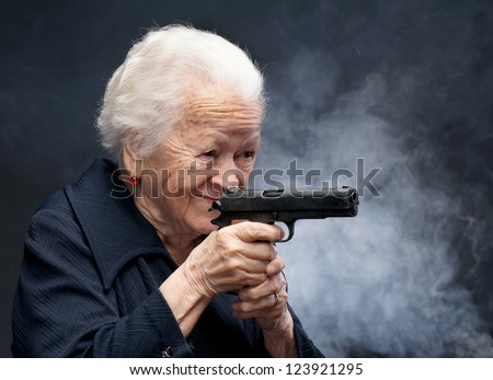 Old woman with pistol on a gray background