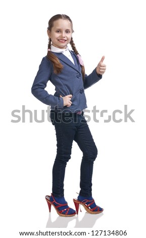 Pretty girl trying on moms shoes and showing yes sign on a white background