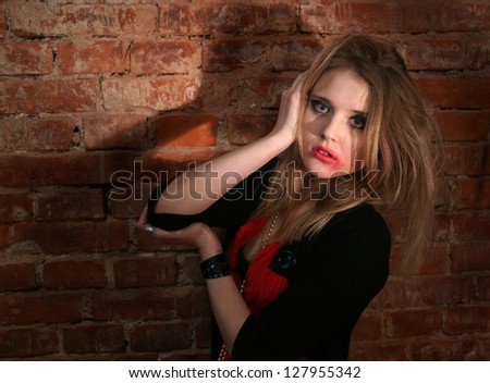 Portrait of sad woman with flowing makeup on a brick wall