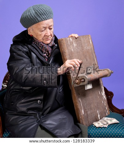 Old woman pressing money on a lilac background