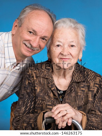 A grown son with his aging mom on a blue background