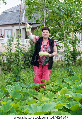 Woman showing marrow squashes on natural background