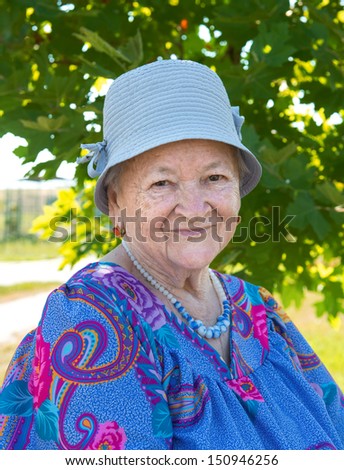 Portrait of smiling old woman in hat in the garden