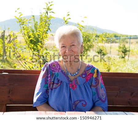Portrait of smiling old woman sitting in the garden