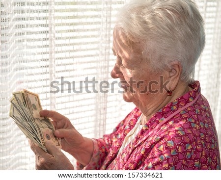 Portrait of old woman holding money in hands
