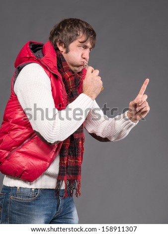 Man blowing a whistle and pointing on a gray background