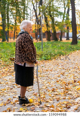 Old woman walking  in the autumn park