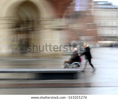 Woman pushing man in a wheelchair in motion blur