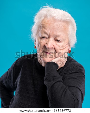 Portrait of old sad woman on a blue background