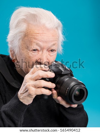 Old woman with photo camera on a blue background