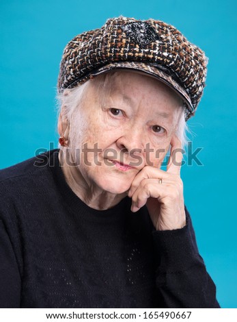 Portrait of old woman in hat on a blue background