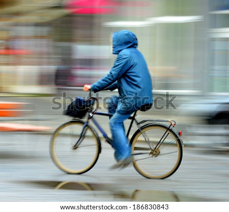 Cyclist on the city roadway in rainy day in motion blur