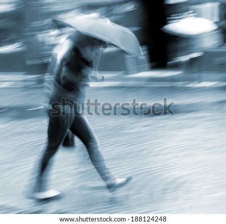 Woman walking down the street in rainy day in motion blur