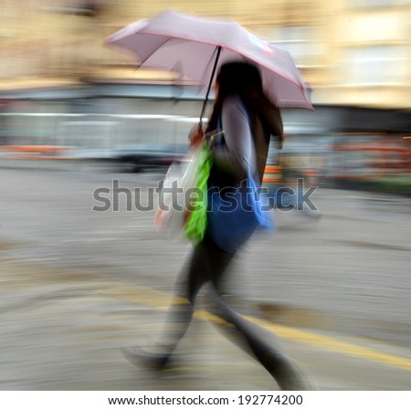 Woman walking in the street on a rainy day in motion blur