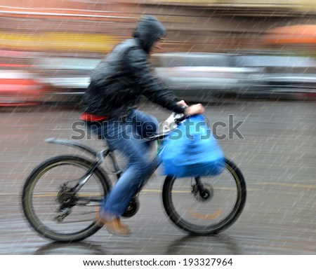 Cyclist in motion riding down the street on rainy day. Intentional motion blur