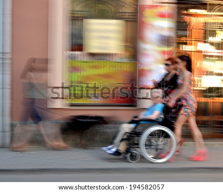Woman pushing old  woman in a wheelchair in motion blur