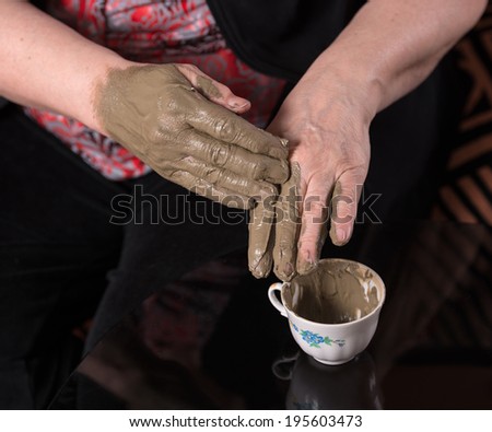 Woman applying spa cosmetic clay cream on hands