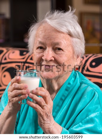 Healthy old woman holding a glass milk