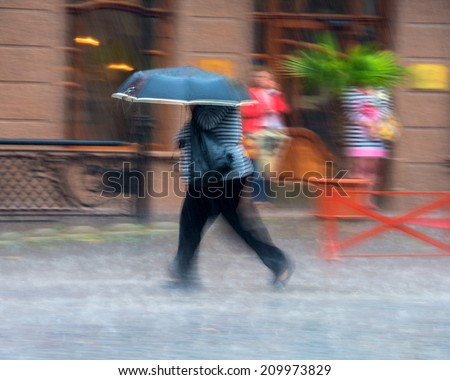 Woman walking down the street on a rainy day in motion blur