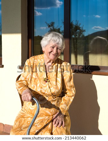 Portrait of smiling old woman sitting near the house